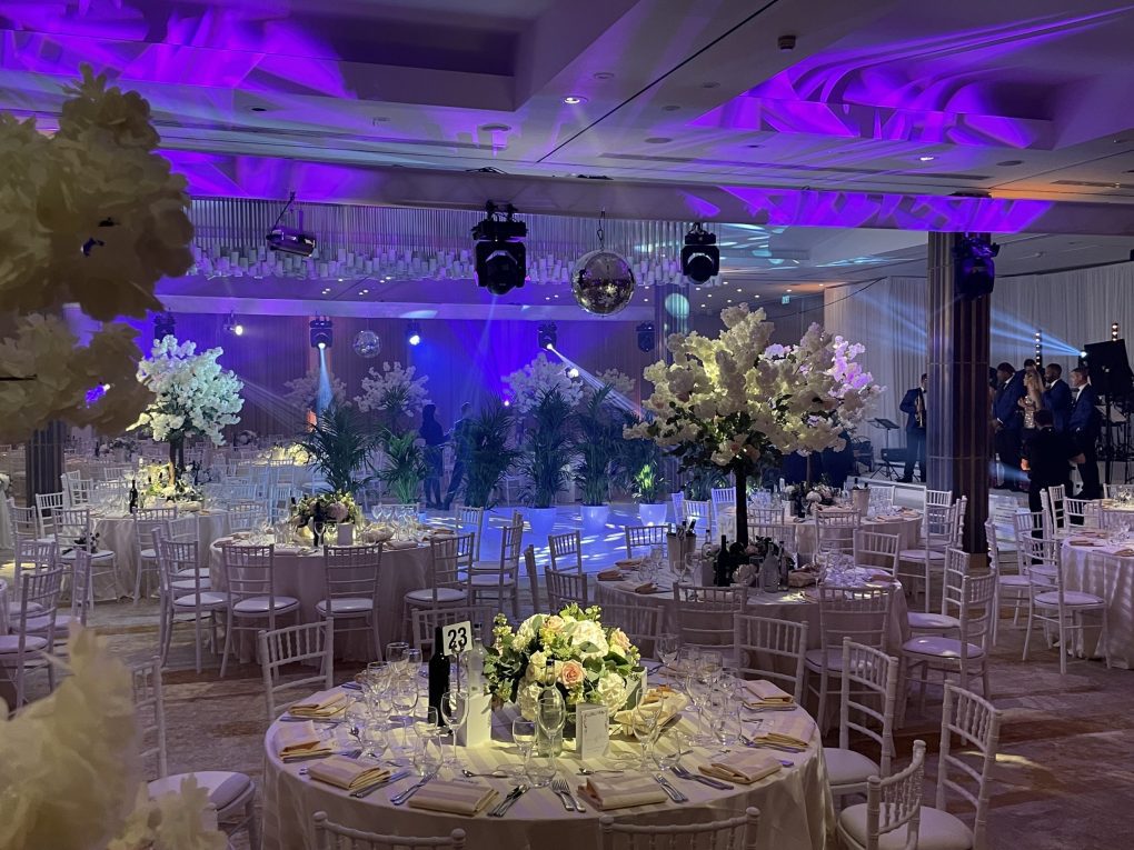 "An enchanting scene of a wedding reception illuminated by stunning and intricate lighting arrangements, casting a warm and romantic glow that enhances the elegance of the venue and creates a magical atmosphere for the celebration of love."