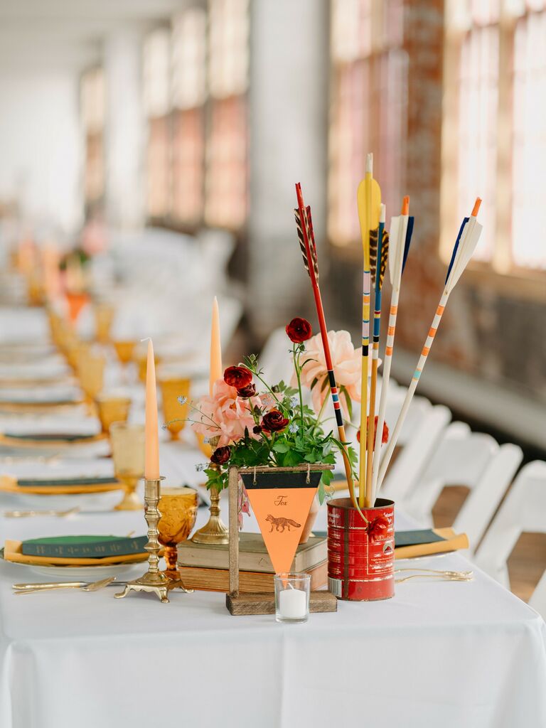 unique wedding centerpiece idea inspired by wes anderson with archery arrows and flowers in vintage coffee tin